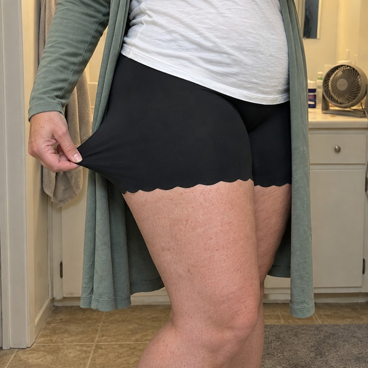 Hand stretching the thin soft fabric of the midnight panty on the thigh